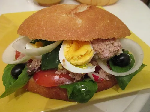 Quel est le nom du sandwich niçois dont l'appellation provençale signifie « pain mouillé » ?